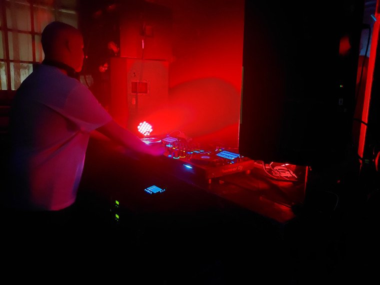 DJ leaning into the mix as lasers sweep the room