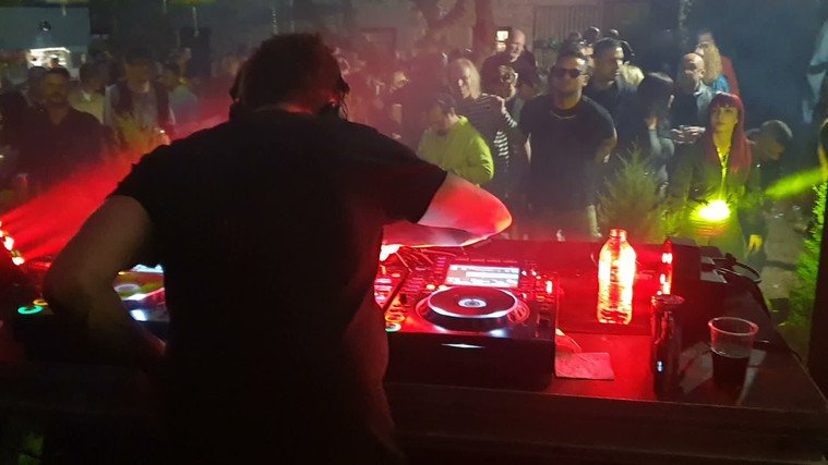 DJ in the booth with the crowd close behind