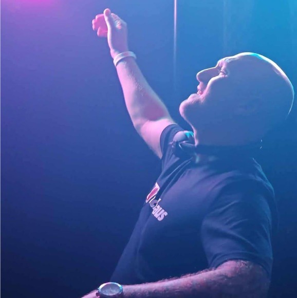 Barry Miller with his arm raised mid set under blue and purple lights
