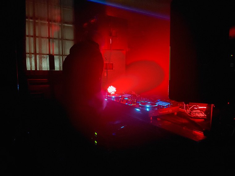 DJ playing in the red-lit stone room