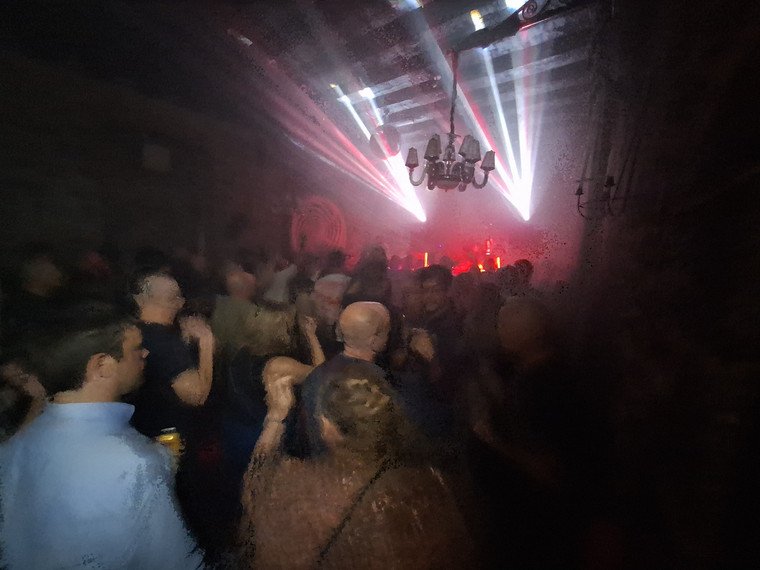 Packed dance floor lit by blue and white lasers